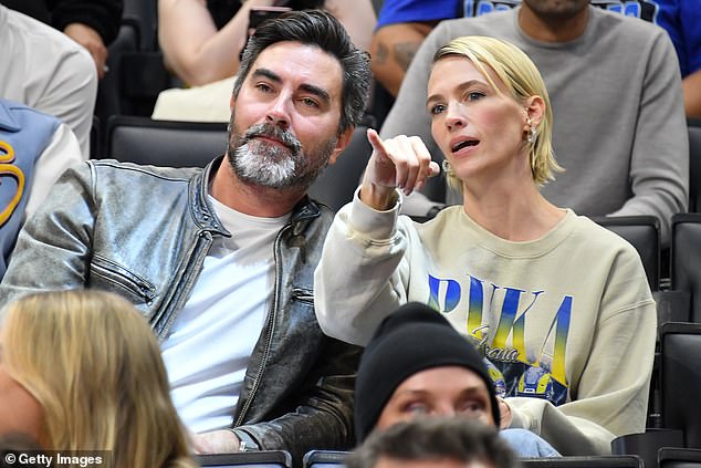 Cute: The actress and model, 45, wore a beige sports jersey and beamed as she sat in the stands with a male friend