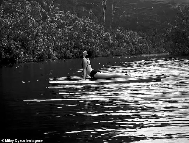 On the water: The 30-year-old singer wore a black bikini top and matching shorts as he balanced on the paddleboard in multiple black and white photos