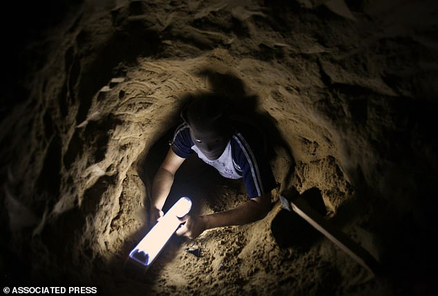 A Palestinian tunnel digger holds a lamp as he makes his way through a smuggling tunnel in Rafah, southern Gaza Strip, on the border with Egypt, in this photo taken on August 8, 2007