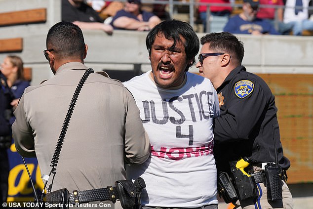 A student protester is seen being escorted from the field