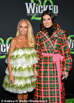 Elegant: In the photos, Menzel, 52, puts on an elegant display, wearing a pink and green plaid trench coat dress with a bubblegum pink belt tied in a bow around her waist