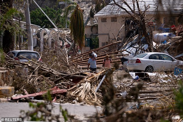 People went for a walk Sunday next to debris and damaged trees in the aftermath of Hurricane Otis in Acapulco, Mexico