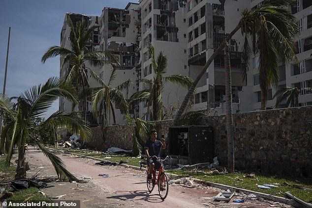 A man cycles past an area damaged by Hurricane Otis in Acapulco on Sunday