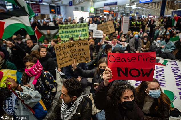 Protesters sit in the station holding signs that read 