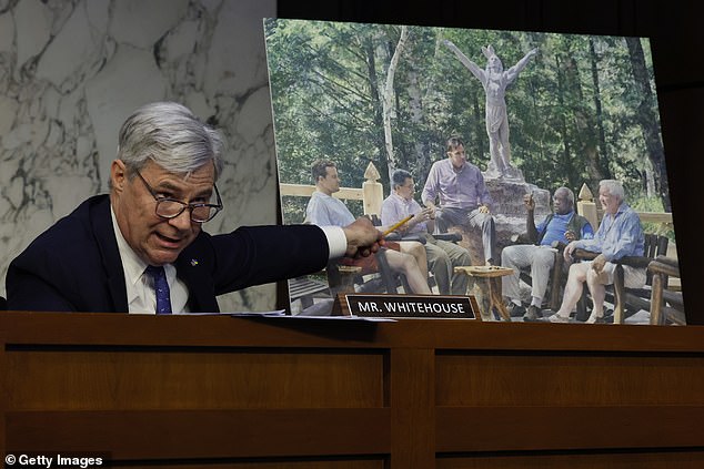 Democratic Senator Sheldon Whitehouse displays a painting of Clarence Thomas (second from right) and Harlan Crow (right) gathered at Crow's Adirondacks resort, Camp Topridge.  The painting can be seen in the building in New York