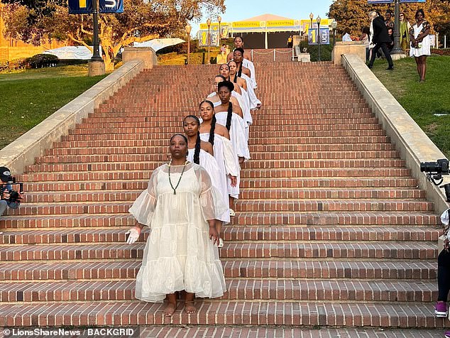 Patrisse Cullors, co-founder of BLM, has made a rare public appearance in a performance art piece featuring a parade of women in white dresses connected by their hair