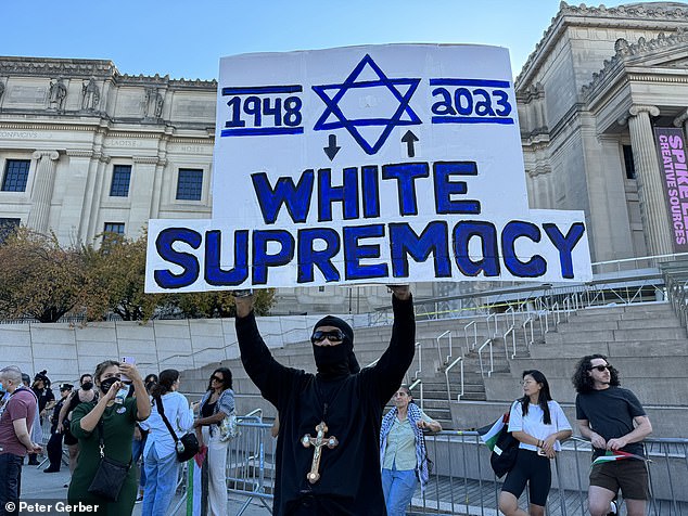 A protester holds up a controversial sign outside the Brooklyn Museum on Saturday afternoon