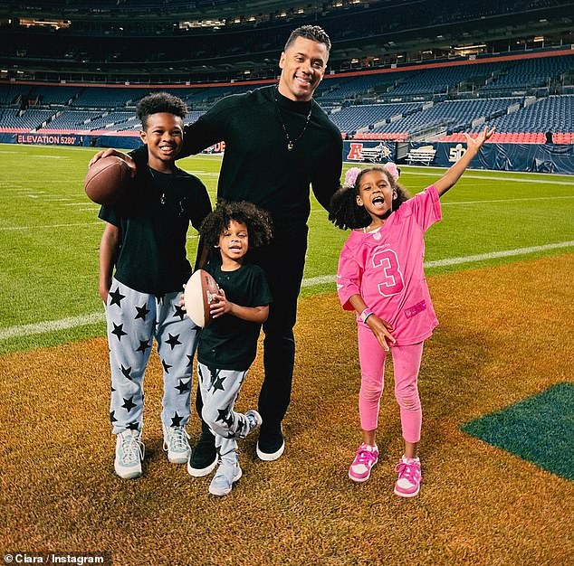 Proud dad: Russell Wilson, 34, looked relaxed in black as he posed for a photo with children Future, nine, Win, three, and Sienna, six