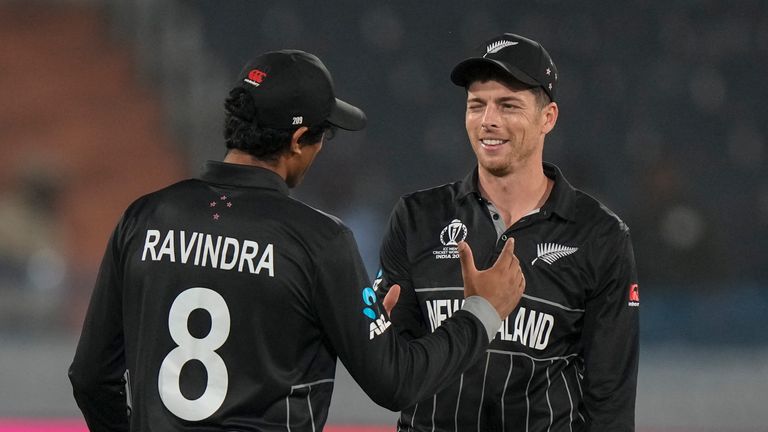 New Zealand's Mitch Santner celebrates with teammate Rachin Ravindra after completing his bowling run 