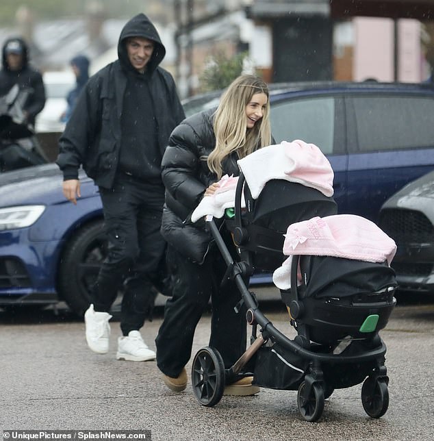 Family day out: Dani Dyer, 27, bundled up in a powder coat as she went for a walk in the rain with her boyfriend Jarrod Bowen, 26, and their twins Summer and Star on Wednesday