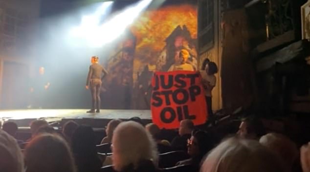 Video shows the theater audience cheering as eco-activists clamber onto the stage holding the group's orange banner in their hands