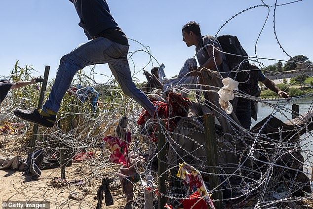 Enforcement encounters with migrants rose to a record high at the U.S. southern border last month.  Pictured: Migrants crossing barbed wire on September 28 in Eagle Pass, Texas