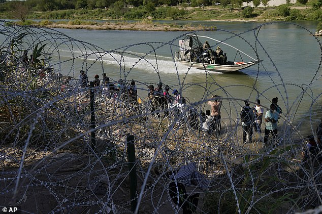 In the photo: Migrants entering the US from Mexico are met along the Rio Grande with concertina wire.  A total of 169 people on the FBI's terror watch lists have been apprehended at the southern border over the past 12 months, according to Customs and Border Protection.