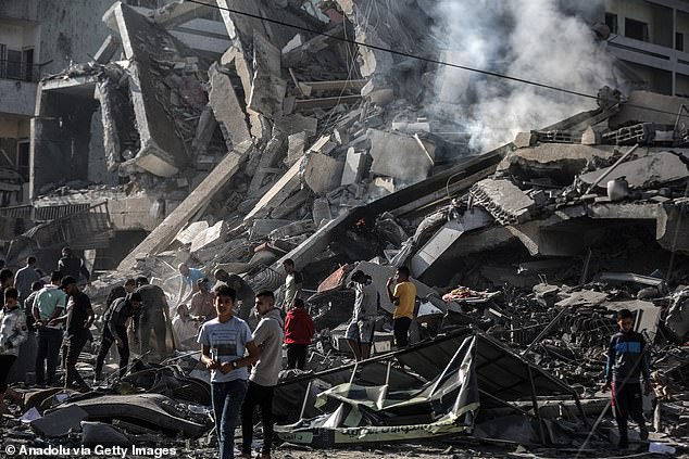 Palestinians are seen on Thursday near rubble of destroyed buildings after Israeli airstrikes on the al-Zahra neighborhood of the Gaza Strip