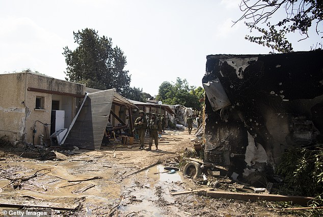 Israeli soldiers patrol near burnt houses after an attack by Hamas terrorists on this kibbutz near the border with Gaza