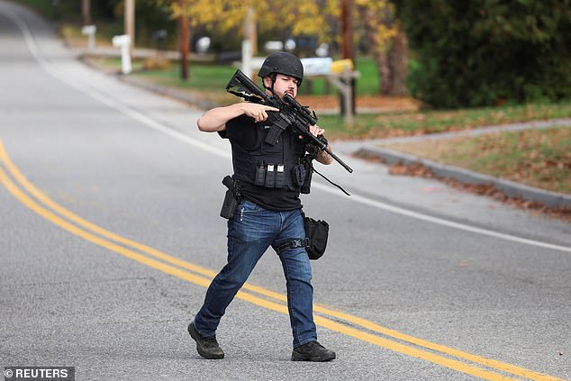 A law enforcement member crosses a road in Lisbon Falls on Thursday