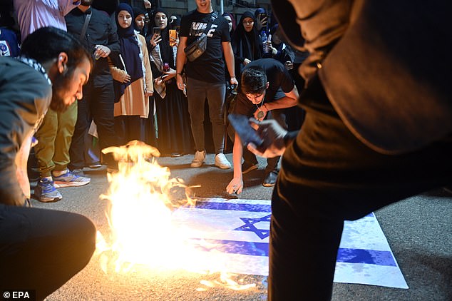 An Israeli flag is burned in celebration by supporters of Hezbollah during the attacks