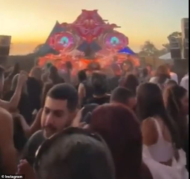 The video begins to show hundreds of revelers enjoying pounding techno music as a soft dawn begins in the background