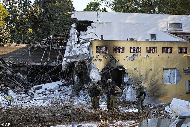 Israeli soldiers walk past houses destroyed by Hamas militants in Kibbutz Be'eri, Israel, Saturday, October 14, 2023