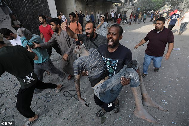 A Palestinian carries a wounded man after an Israeli airstrike on northern Gaza