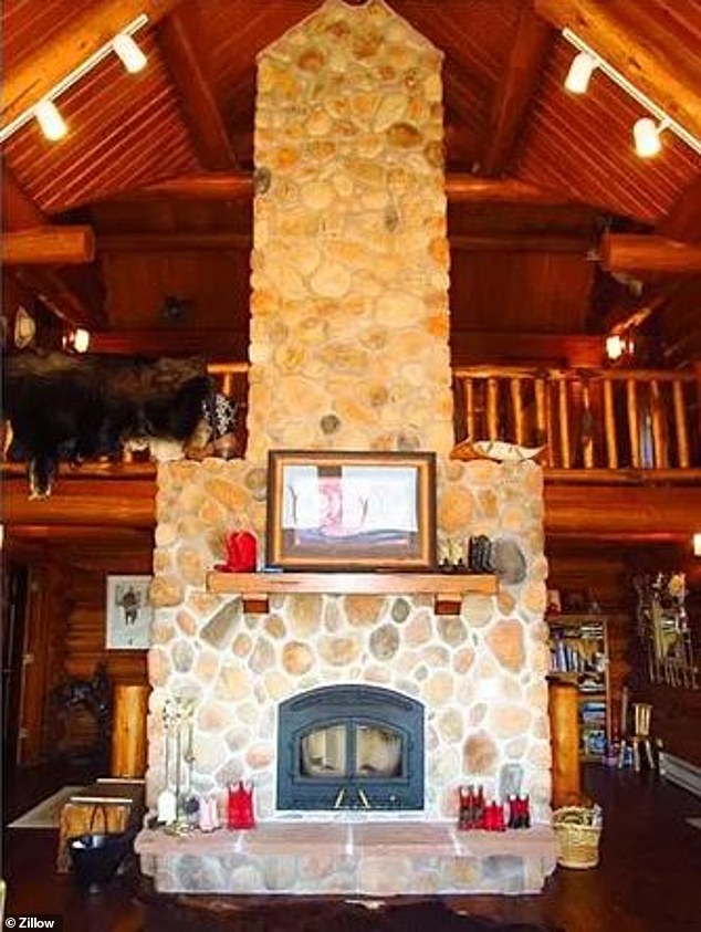 The log cabin-style children's home features a large stone fireplace that extends visibly beyond the open balcony on the second floor