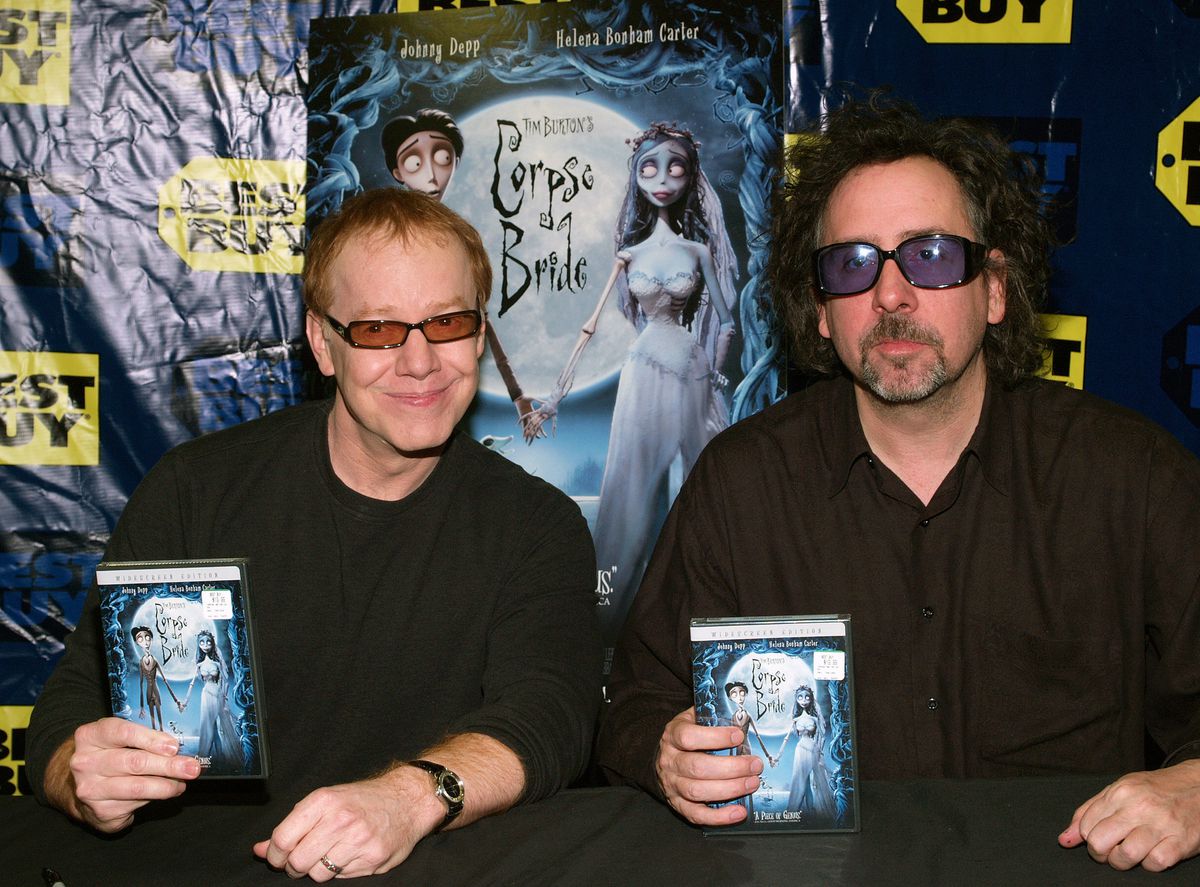 Tim Burton and Danny Elfman smile as they hold up signed copies of the Corpse Bride DVD at Best Buy in West Hollywood in 2006