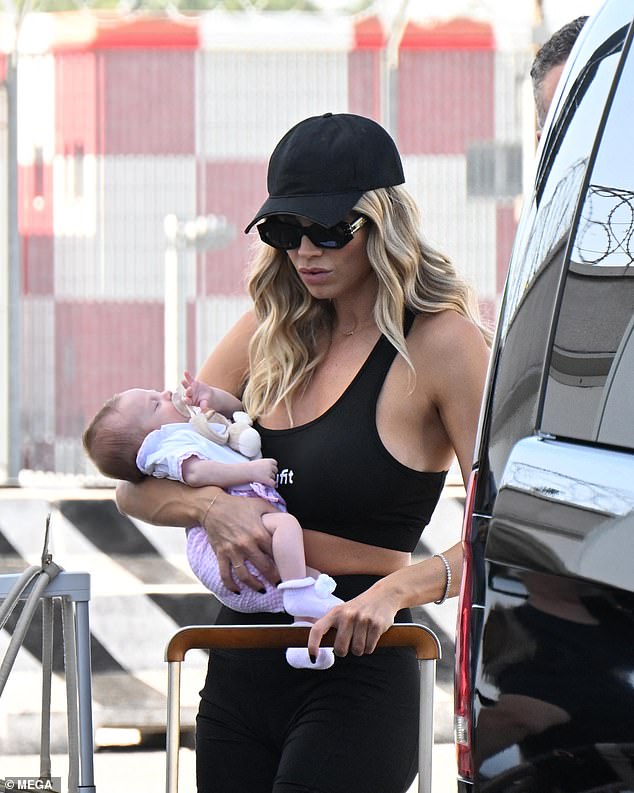 New mum: Loris Karius' girlfriend Diletta Leota, 32, held the couple's daughter, 9 weeks old, as they arrived at Milan airport on Friday ahead of their trip