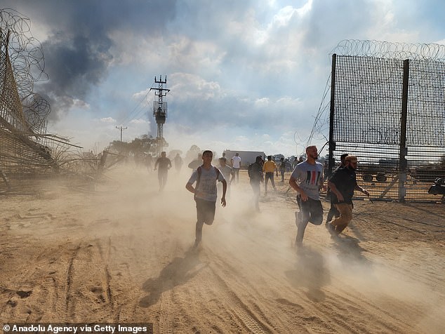 Palestinians rush through a cap after taking down the fence on the Israel-Gaza border and enter Israel following clashes and attacks in Gaza City, Gaza on October 7