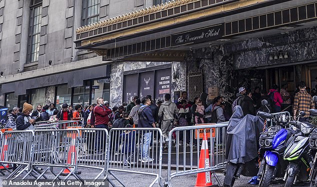 Asylum seekers line up in front of the historic Roosevelt Hotel, converted into a city-run processing center, on September 27