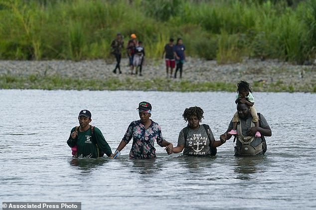Haitian migrants wade across the Tuquesa River after trekking through the Darien Gap in Bajo Chiquito, Panama, Wednesday, October 4, 2023