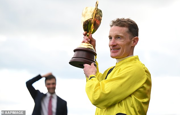 Zahra holds up the Caulfield Cup trophy after a race he won't soon forget