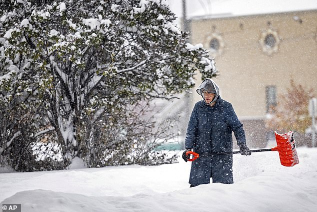 A woman clears snow in Helena, Montana, as the first major winter storm of the season dropped more than a foot of snow on the area