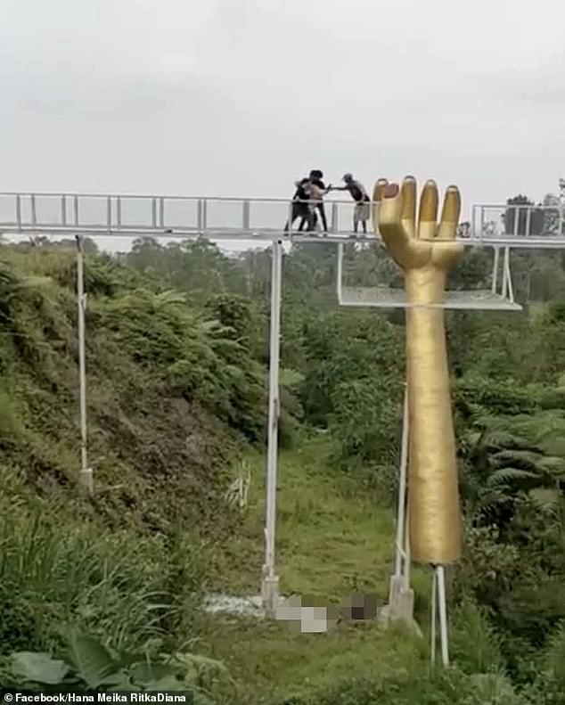 Brave onlookers help a stranded tourist to safety after the Geong Bridge shattered in Indonesia