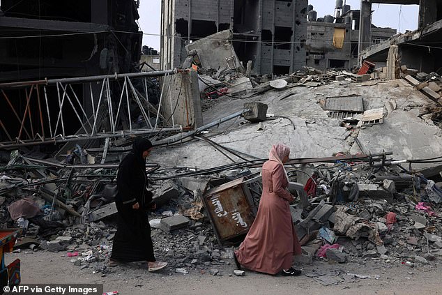 Women walk past a destroyed building in the southern Gaza city of Rafah on Saturday