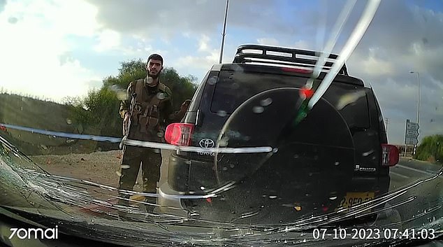 In the footage, the car slowly swerves to the left and finally comes to a stop when it slams into the back of another vehicle which is pulled over to the side of the road - suggesting the driver has been shot dead.  Militants (pictured) are then seen checking the car for survivors