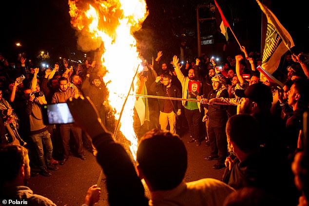 Protesters burn an Israeli flag during an anti-Israel protest in front of the British Embassy in Tehran, Iran, early Wednesday, October 18, 2023