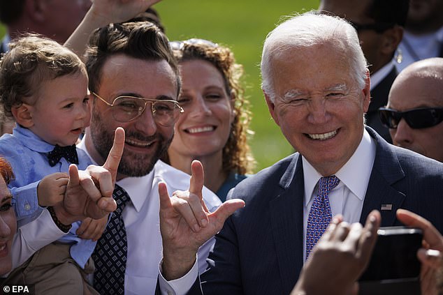 President Joe Biden signs 'I love you' in American Sign Language while taking photos with guests at an event celebrating the Americans with Disabilities Act