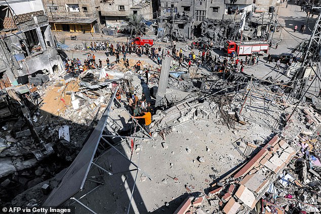 People stand by as civil protection workers search for victims and survivors in the rubble of a building hit by an Israeli bombardment on Tuesday in Rafah in the southern Gaza Strip