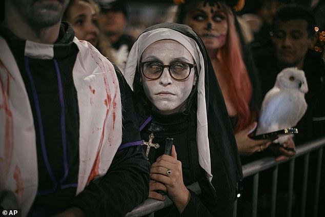 A woman dressed as a creepy nun waits for the parade along Sixth Avenue