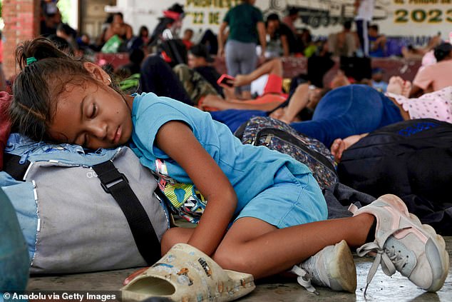 A migrant girl sleeps while other caravan members rest after a long day of travel