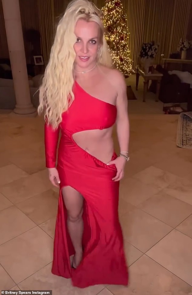 Dress #4!  Spears then donned her slim 6-foot figure in a red dress, exposing her arm, abs and legs as she posed in front of her Christmas tree in a clip to Madonna's 2012 song I'm Addicted.