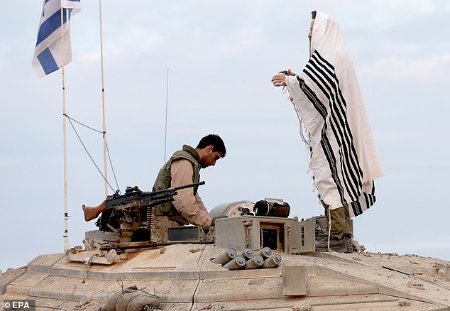 Israeli soldiers pray while sitting on a tank in the Western Galilee on Monday while guarding the border with Lebanon