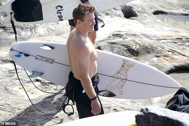 The weekend sports reporter from 10 News First walked across the sand looking pale with his black wetsuit rolled up to his waist.  Mackinnon was all smiles as he walked out to sea with his white surfboard, ready to brave the big swell at Sydney's popular beach