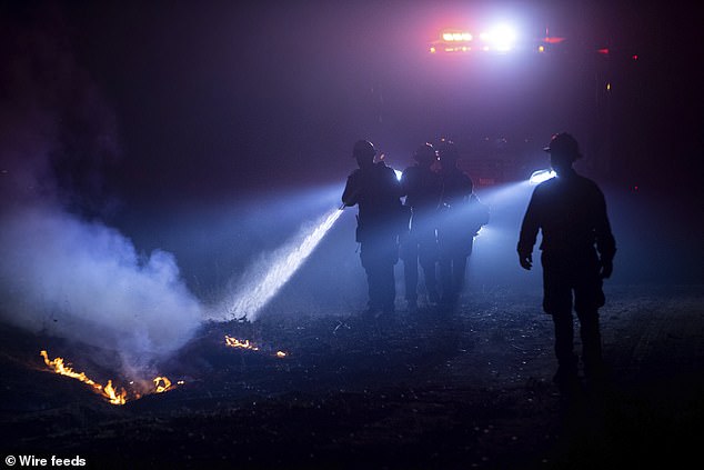 Firefighters work to extinguish flames caused by the Highlands wildfire