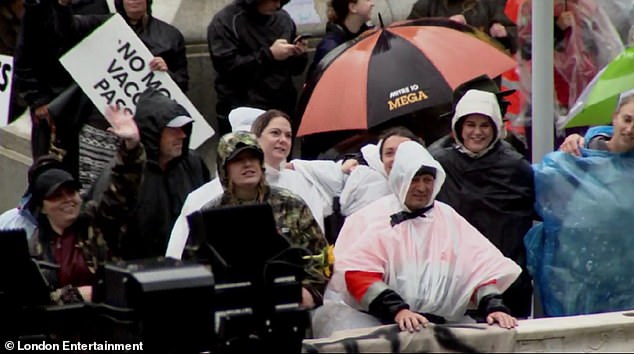 Hilarious: The film shows a crowd of anti-vaxx protesters belting out James' 2005 hit You're Beautiful as they danced together in the rain