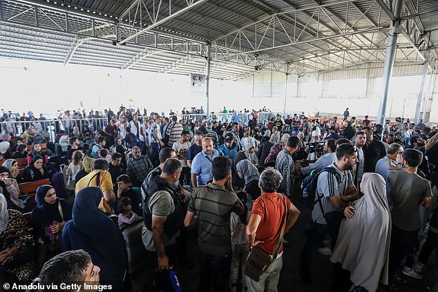 Palestinians with foreign passports wait at the Rafah border gate to enter Egypt