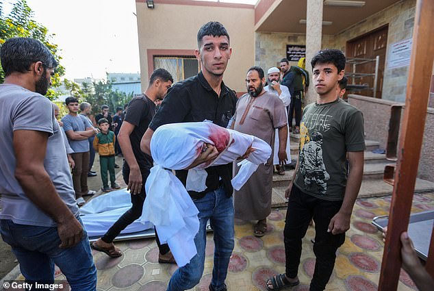 A man carries the body of a child killed in Israeli airstrikes in Khan Yunis, Gaza on Wednesday