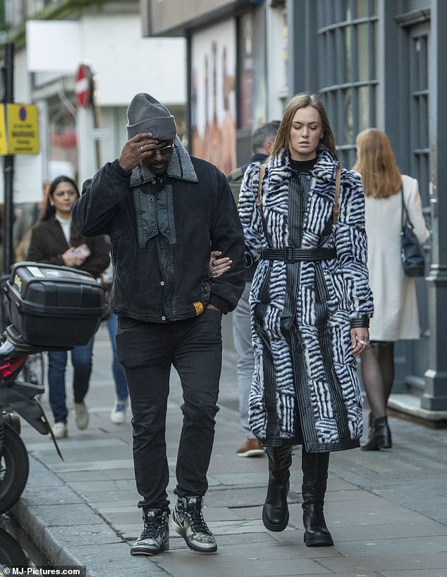 Couple: The pair chatted intently as they walked down the busy street before stopping to grab both a coffee and a kiss