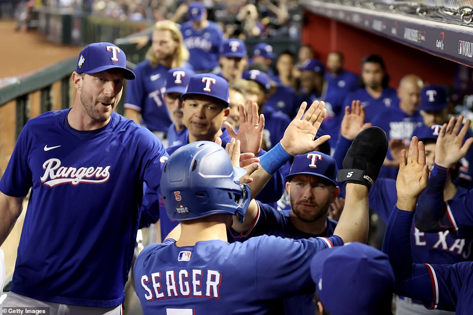 Corey Seager (below) celebrates with teammates after scoring a run in the seventh inning at Chase Field in Phoenix