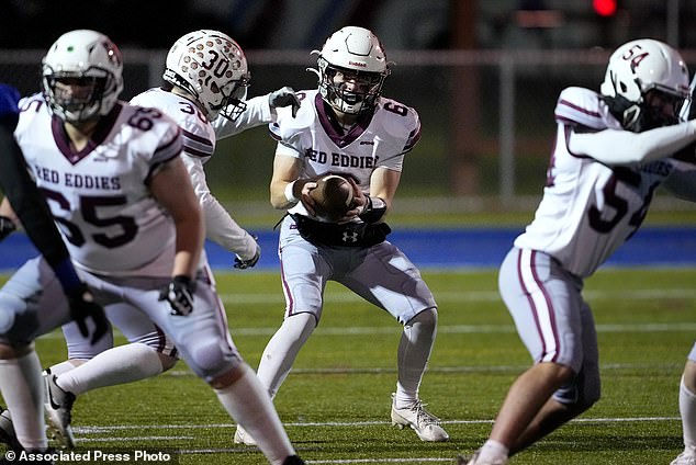 Edward Little High School quarterback Kade Masselli takes the photo during the rivalry game